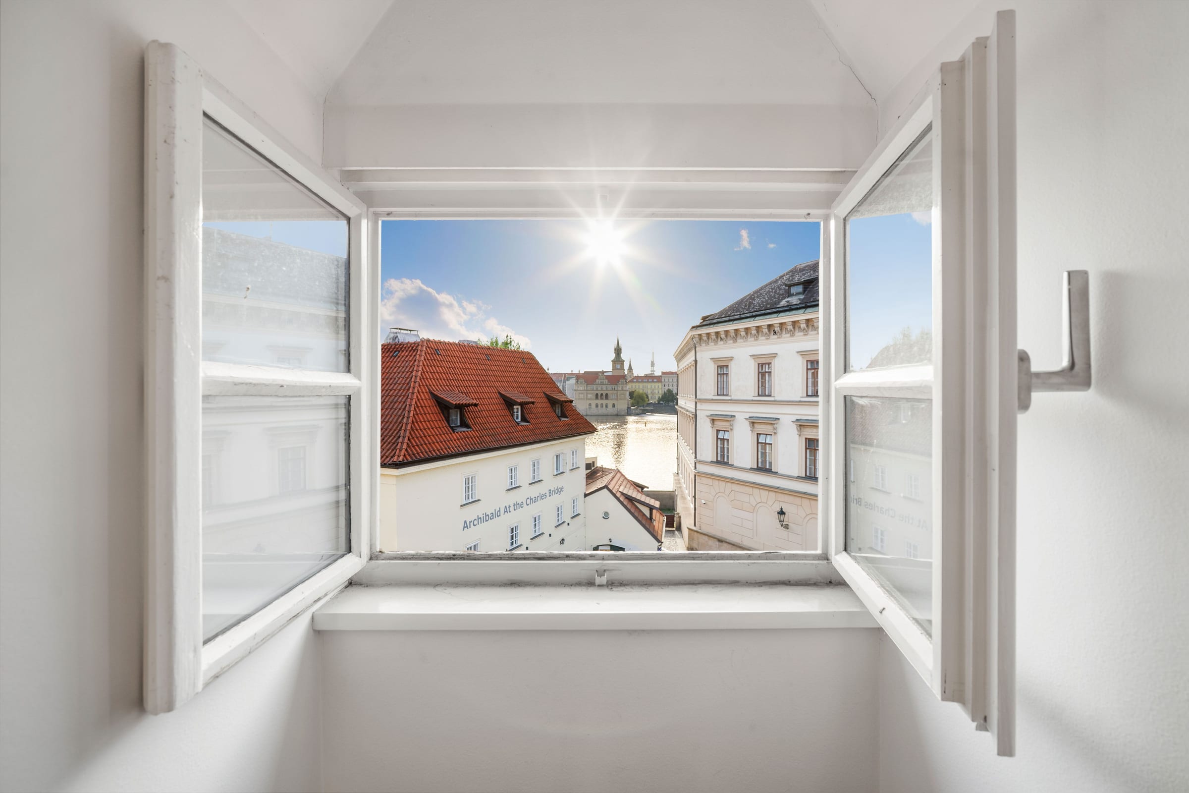 Offenes Fenster mit Blick auf die Dächer und die Moldau